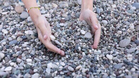女人的手在海滩上收集卵石