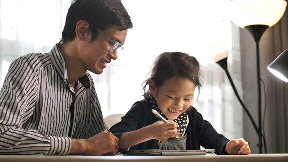 亚裔父亲和女儿做家庭作业的数字平板电脑在家里