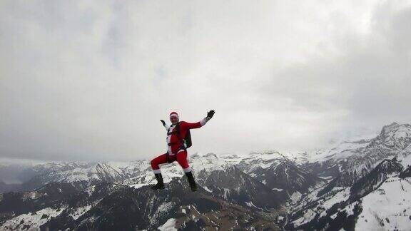 穿着圣诞老人服装的自由落体跳伞者向雪山坠落