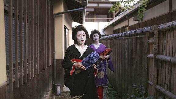 两名艺妓一起走在京都祗园狭窄的街道上