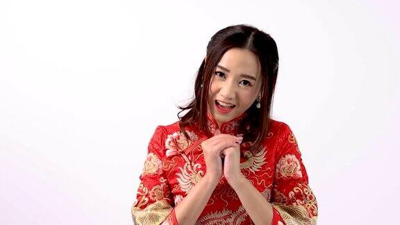 年轻的亚洲女性穿着红色旗袍在中国新年当天表现出尊敬和问候