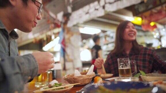 亚洲妇女欢呼与啤酒与朋友在日本餐厅