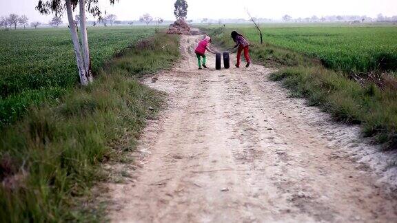 小女孩带着轮胎在乡村公路上玩耍和奔跑