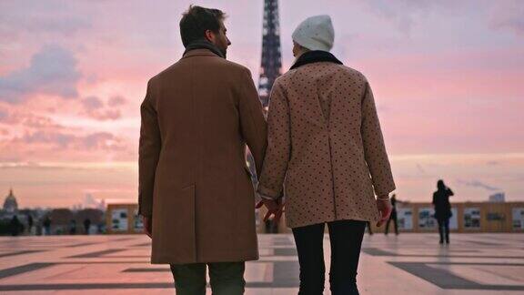 法国巴黎一对年轻夫妇手牵着手走向埃菲尔铁塔