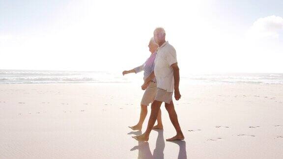 一对浪漫的老年夫妇在夏天沿着海滩散步