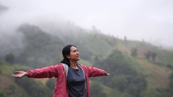 年轻的亚洲女性在山顶愉快地呼吸着新鲜空气