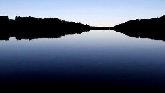 暮色中平静的山湖的轮廓