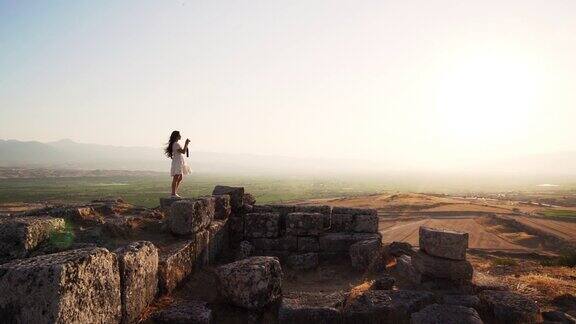 一名女游客摄影师正在为棉花堡希拉波利斯的古代遗迹拍照
