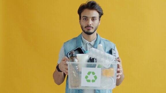印度男子的肖像拿着回收的塑料垃圾盒看着相机