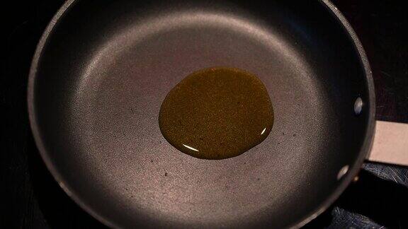 将橄榄油缓缓倒入煎锅中然后摊开