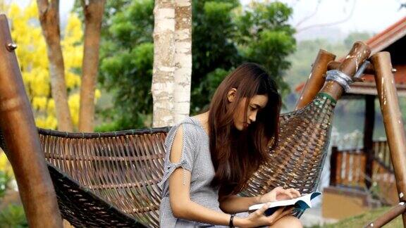 一个年轻的亚洲女人在吊床上看书