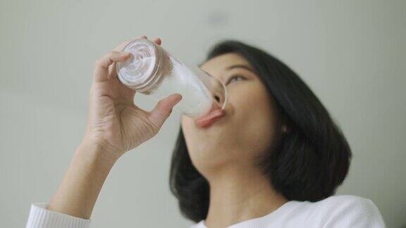 亚洲女人喝着一杯水