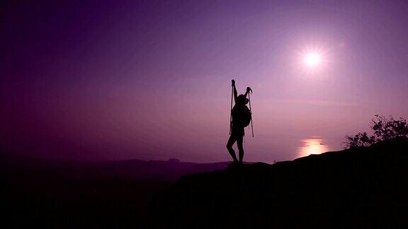 欢呼的女徒步者在日落山顶张开双臂