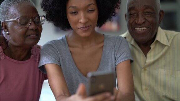 一个女人向一对老年夫妇展示手机人们微笑着玩