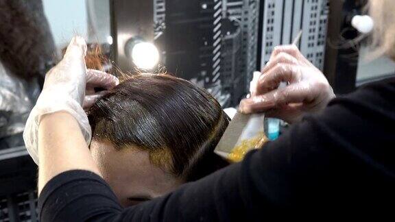 东方女孩在理发店染发美发师在她头上涂颜料头发护理关闭了4k25fps