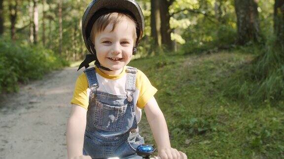 快乐的小男孩在夏天的公园里骑自行车
