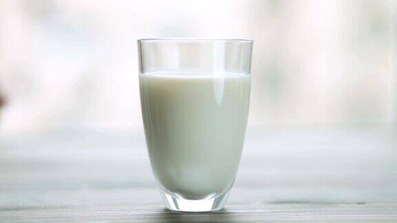 手把一杯牛奶放在木桌上