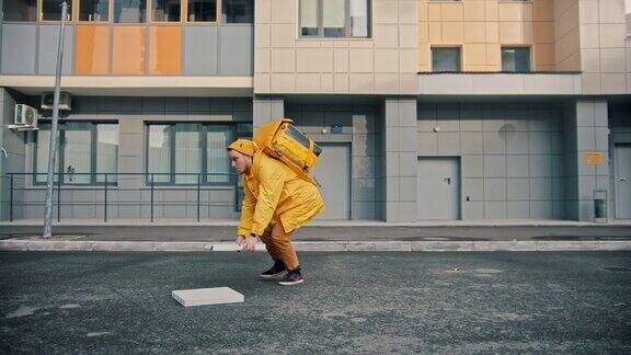 一名身穿黄色衣服的快递员送餐将披萨盒扔在地上继续送餐