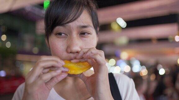街头小吃-年轻女子吃芒果在瑶华路曼谷泰国