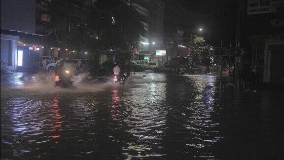 晚上下雨时摩托车穿过被水浸透的街道
