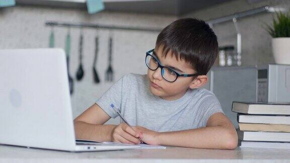 在线学习远程课程在家教育儿童科技男孩用教科书做家庭作业在家里用数码平板电脑