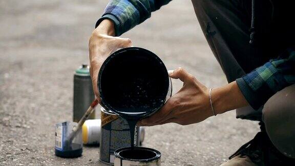 艺术家把一种黑色颜料从一个罐子倒到另一个罐子里