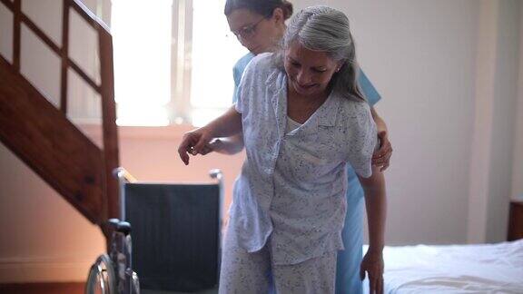 女护士帮助老年女病人坐上轮椅