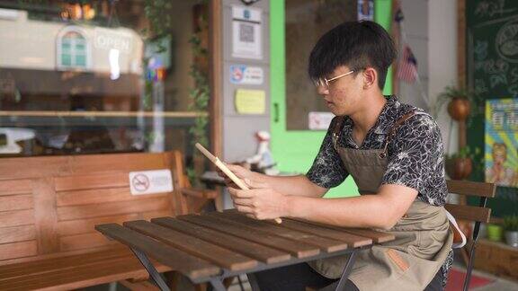 亚洲华人年轻的咖啡馆咖啡师服务员自助餐厅的工人用粉笔在黑板上写“开放”字准备在早上的咖啡馆餐厅营业