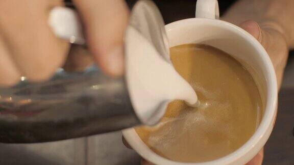咖啡师把牛奶倒进热咖啡里在咖啡馆里画叶子