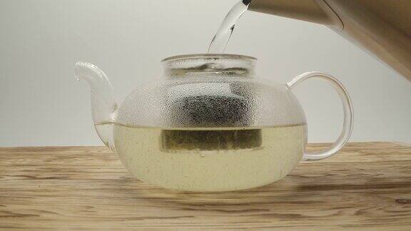 将开水从茶壶中倒入木桌上的白茶中