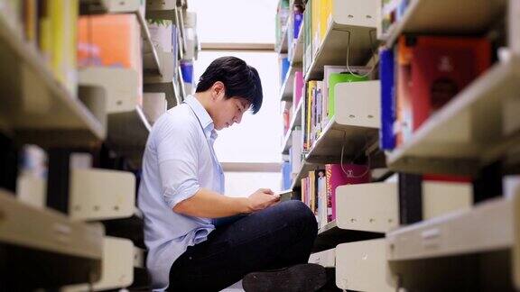 亚洲男大学生在图书馆地板上看书做研究
