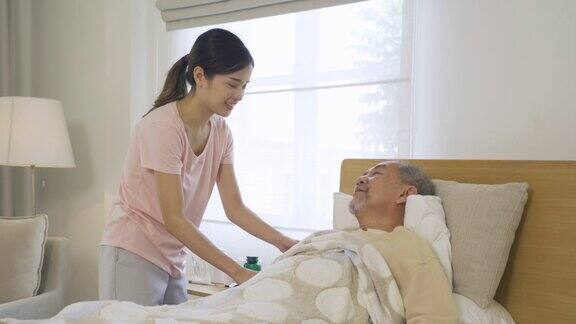 快乐的女人护士女儿说话鼓励生病的老人老人躺在床上在家里或家里的医疗保健治疗亚洲泰国人的生活方式家庭