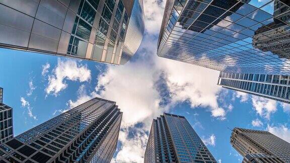 4K时间流逝芝加哥市中心摩天大楼的上升角度与高楼之间的云反射伊利诺伊州美国商业和透视概念
