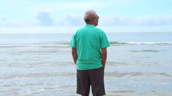 亚洲老人独自站在沙滩上思考人生