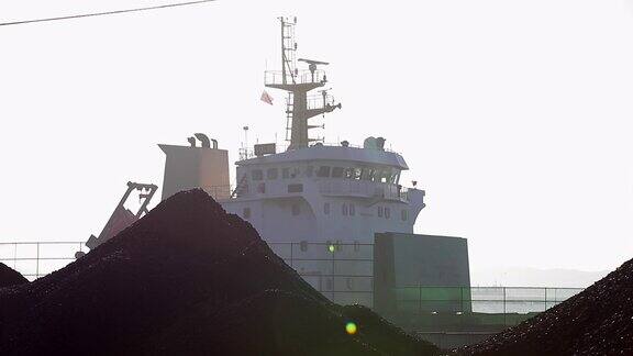 一艘海运货轮站在港口的煤堆后面