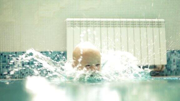 快乐微笑的幼童是跳跃和跳水下的水在游泳池一个水下拍摄Slowmotion