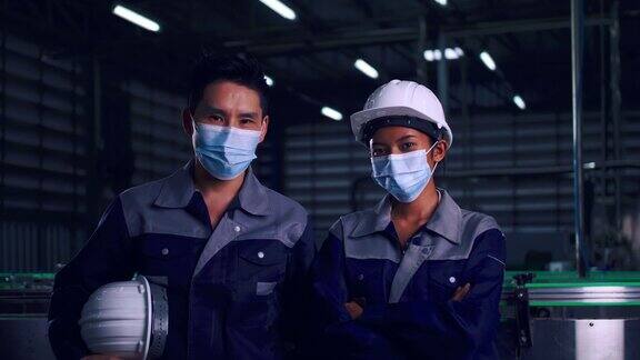 在新冠肺炎疫情下亚洲工程师团队戴着医用口罩在工厂一起工作