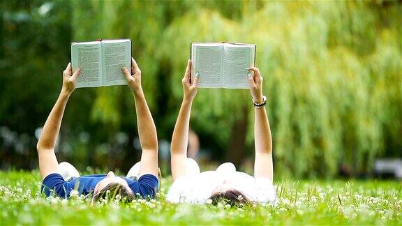 一对轻松的年轻夫妇躺在草地上看书