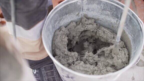 建筑工将砂浆和砖混合在一起在桶中混合溶液