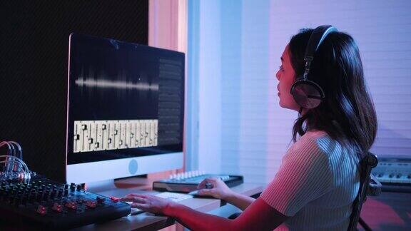 音乐制作工作室生产商在录音棚工作的女人用电脑和混音器在录音棚里创作音乐音乐制作