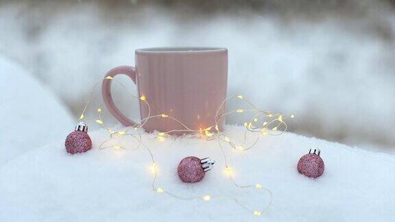 一杯热饮圣诞球在雪地上