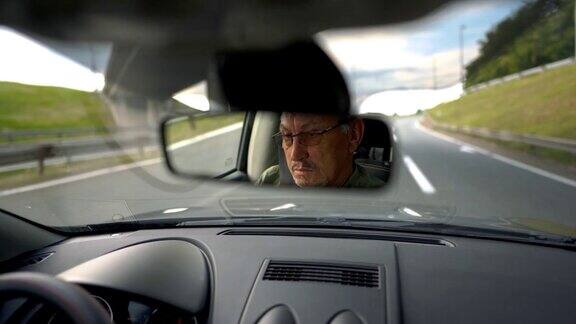 有经验的戴眼镜的老人在高速公路上开车