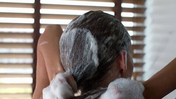 女性在浴室用洗发水洗头的后视图