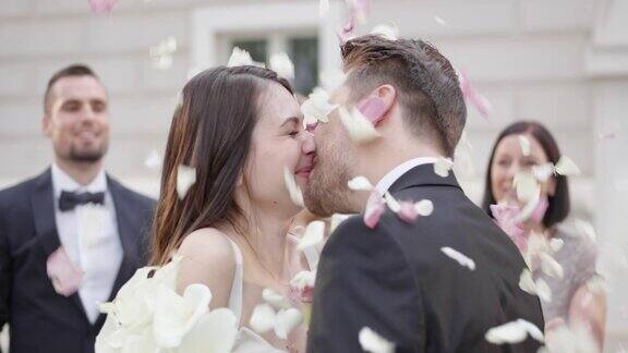 新婚夫妇亲吻而婚礼上的客人扔花瓣