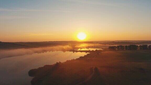 日落时分的空中风景电影无人机镜头飞过乌克兰的一条河田野在薄雾中