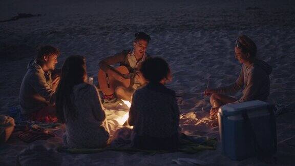 日落时分的海滩派对和朋友们一起篝火和烤棉花糖
