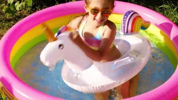 一个戴着太阳镜的女孩在一个小小的充气游泳池里嬉戏