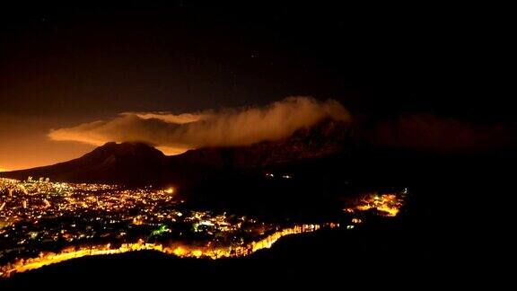 在南非开普敦的桌山上方移动的云的时间间隔夜晚城市灯火通明