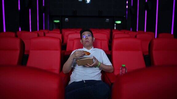 亚洲中国成熟男子一边在电影院看电影一边享受零食
