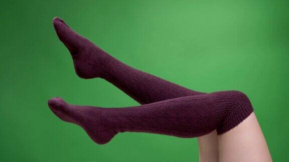 近距离拍摄的女性腿在可爱的红色袜子的颜色与背景孤立在绿色